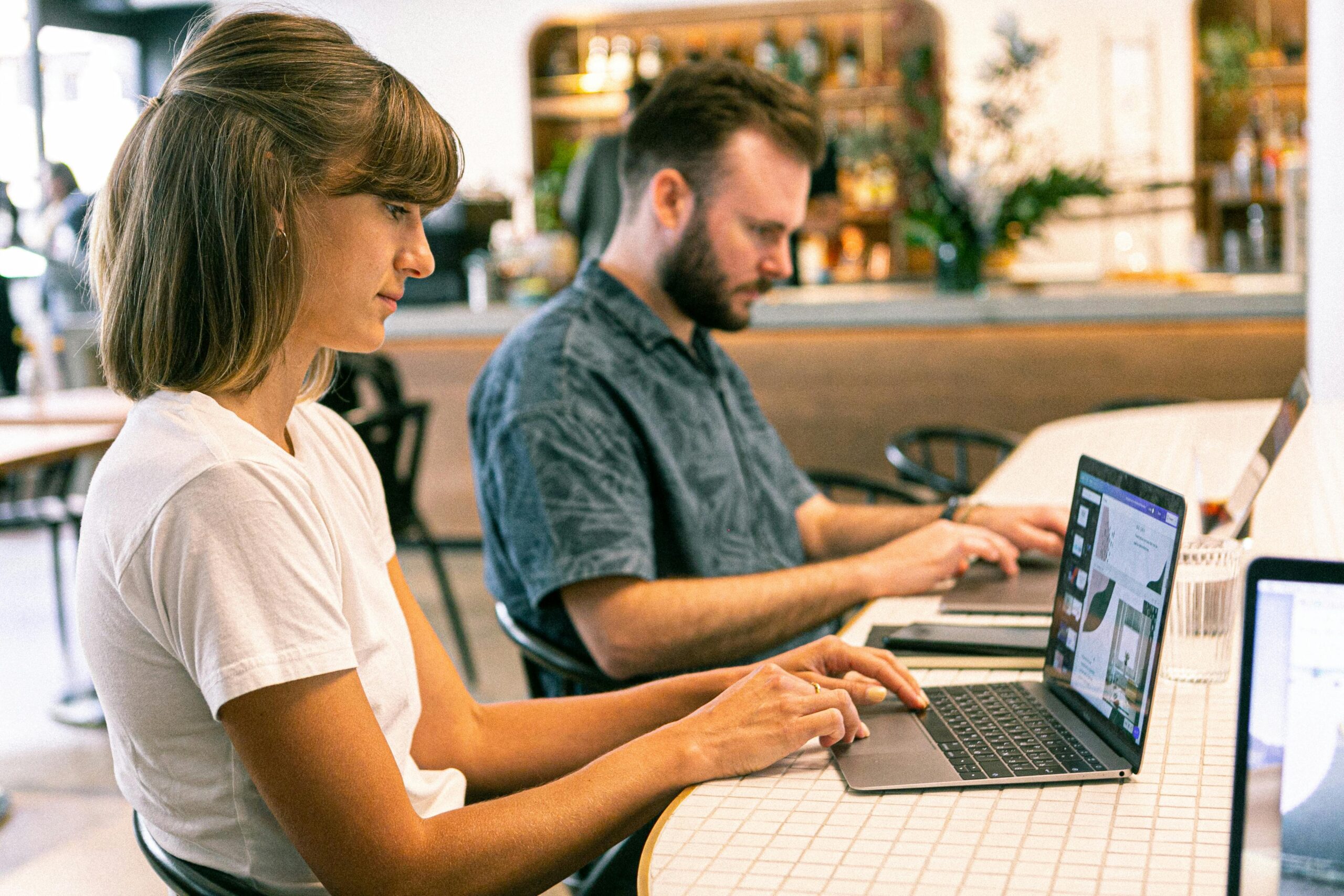 Creative professionals working on design projects using laptops in a modern workspace.