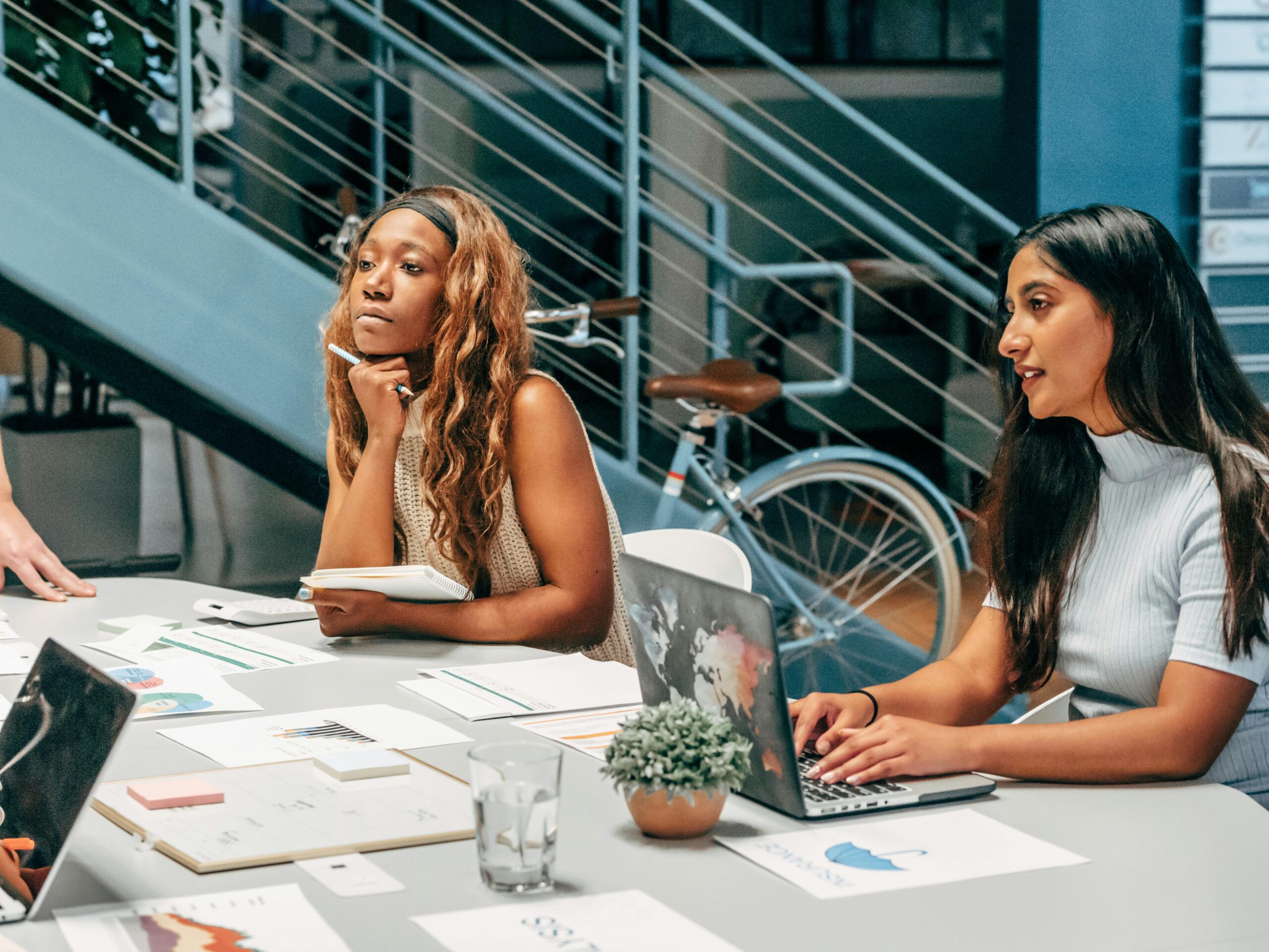 Focused young professionals collaborating at a modern workspace, engaged in a learning discussion.